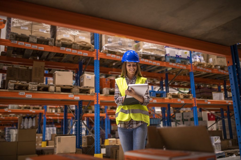 Vrouwelijke magazijnmedewerker met veiligheidshelm die inventaris controleert – logistieke vacatures Venlo (NFA Recruitment).