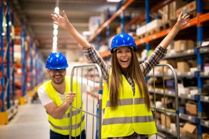 Magazijnmedewerkers in veiligheidshesjes en helmen die glimlachend samenwerken in een distributiecentrum in Venlo.